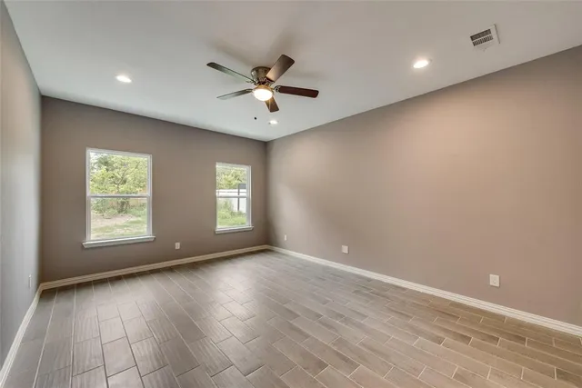 an empty room with wooden floor and windows