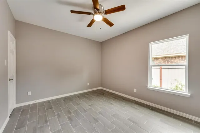 an empty room with windows and fan