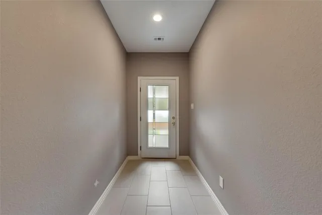 a view of an empty room with a window and a kitchen