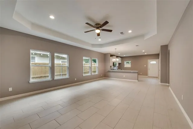 an empty room with chandelier fan and windows