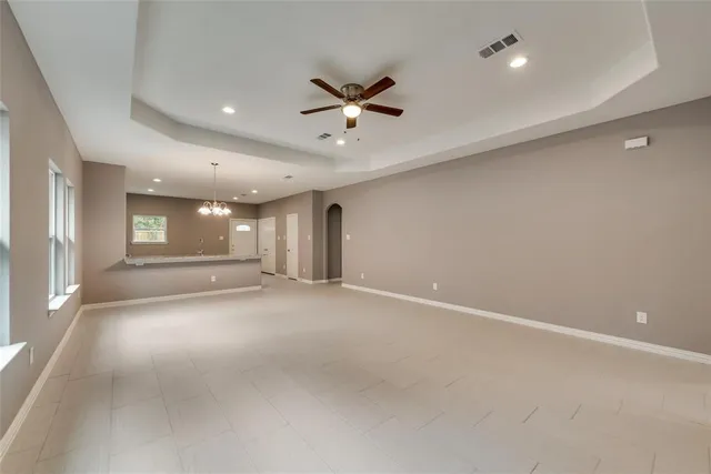 a view of an empty room with a window and a kitchen