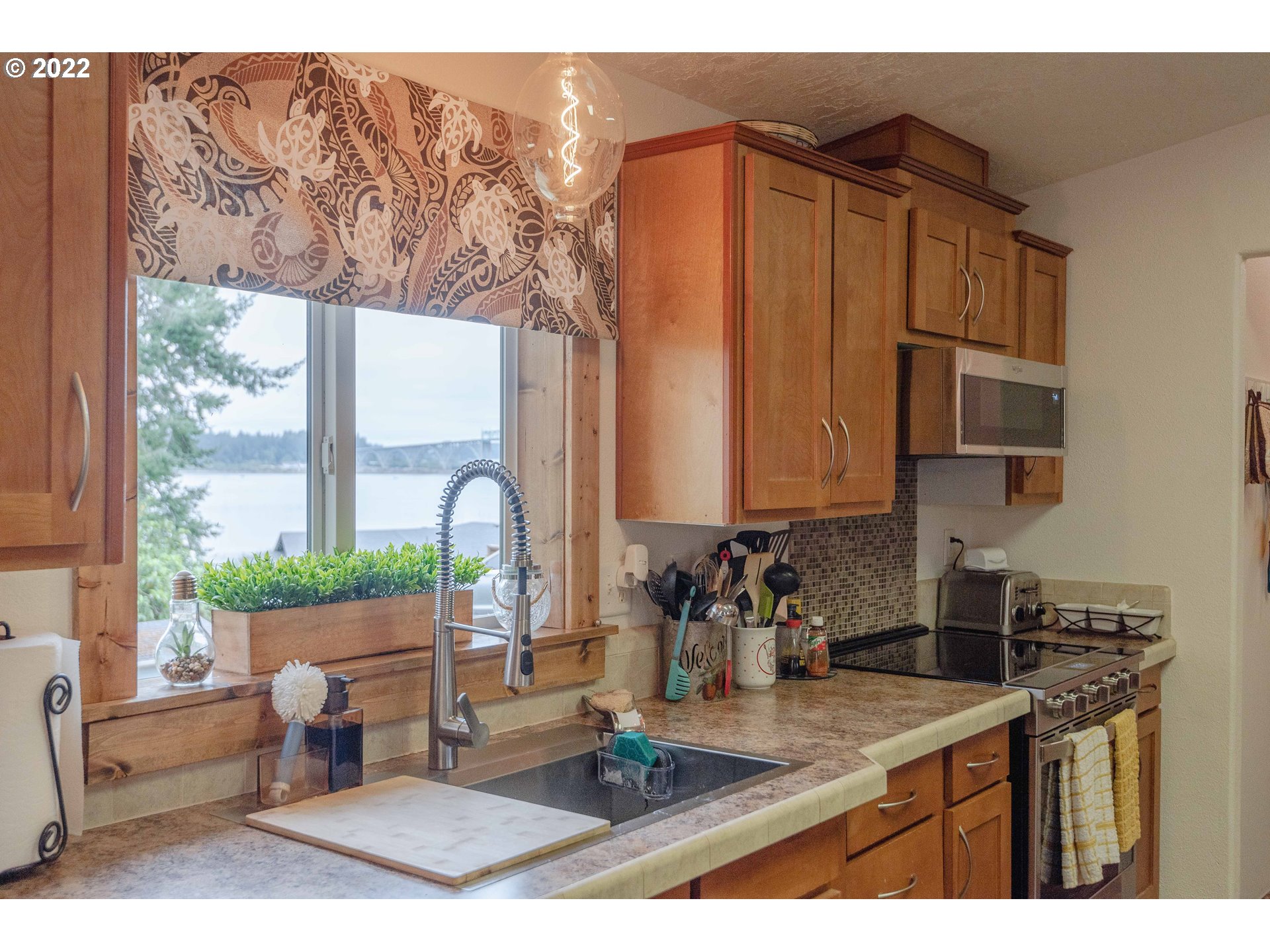 67506 East Bay Road North Bend, OR 97459 - Photo 9 of 31 a kitchen with a stove a sink and a microwave