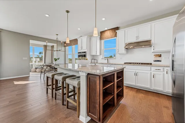 a kitchen with stainless steel appliances granite countertop a stove a sink dishwasher and a refrigerator with wooden floor