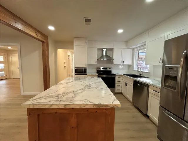 a kitchen with granite countertop a refrigerator a stove top oven and sink