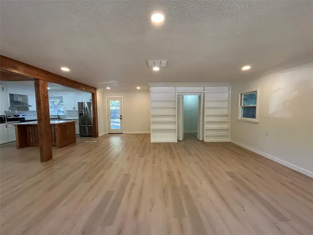 a view of a big room with wooden floor and a kitchen
