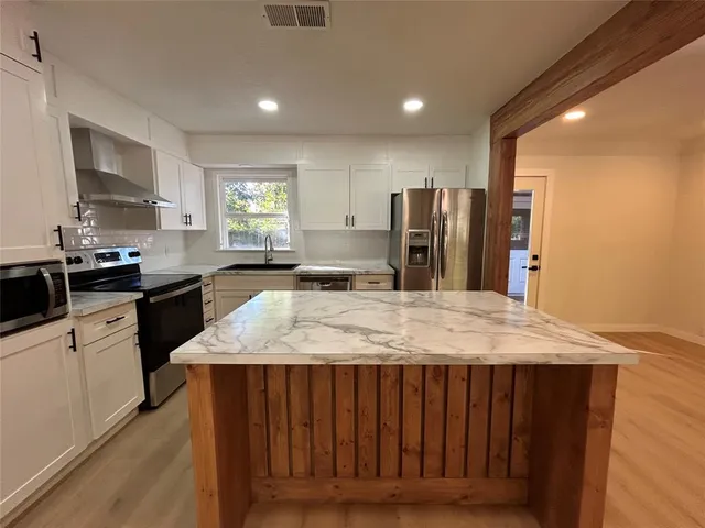 a kitchen with stainless steel appliances granite countertop wooden cabinets a stove top oven a sink and dishwasher