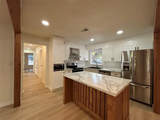 a kitchen with stainless steel appliances granite countertop a refrigerator a sink and a stove