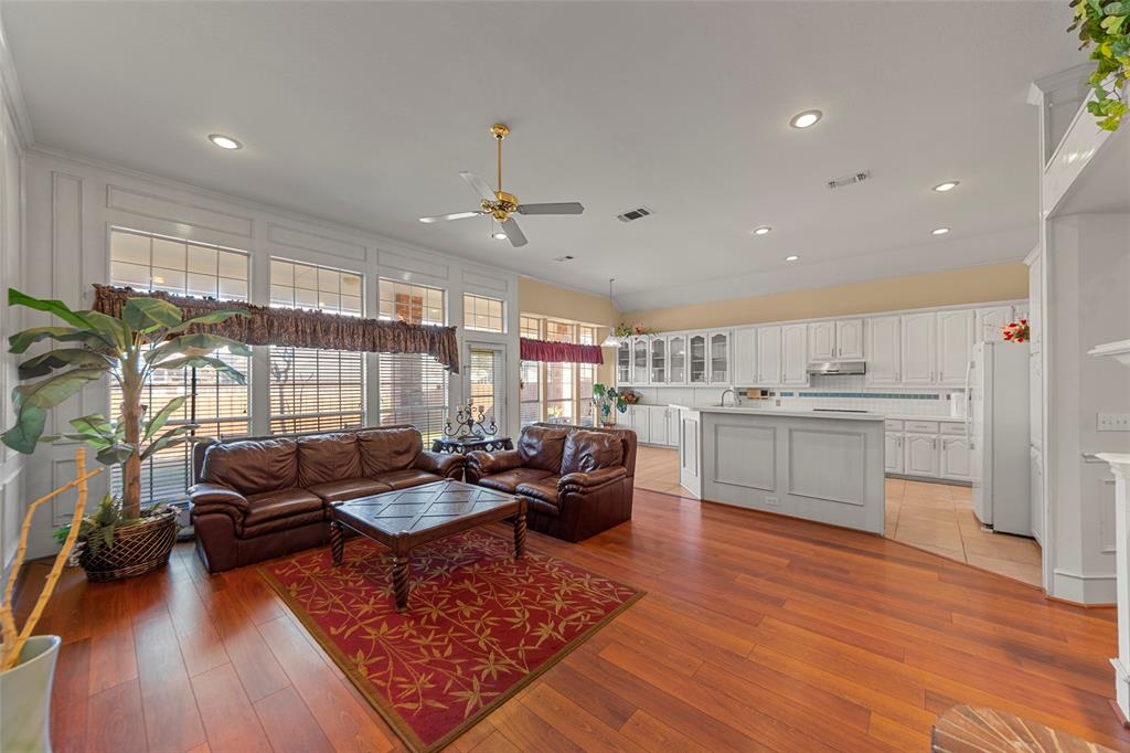 3308 North Spring Drive Richardson, TX 75082 - Photo 7 of 38 The family room showcases soaring ceilings and elegant paneled walls that create a grand yet inviting atmosphere. Rich wood-like flooring adds warmth and durability, flowing seamlessly throughout the space. A charming brick fireplace serves as a cozy focal point, while large windows fill the room with abundant natural light. Spacious yet comfortable, this inviting area is perfect for both everyday living and entertaining.