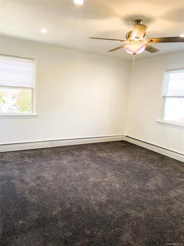 an empty room with a window and a ceiling fan