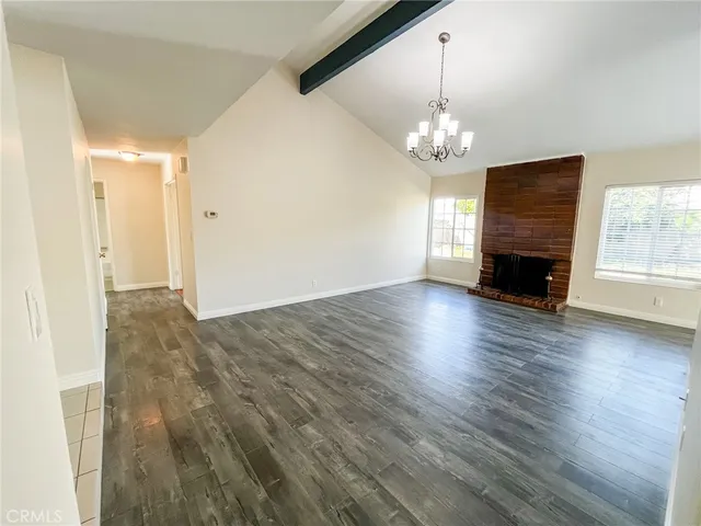 an empty room with wooden floor chandelier and windows