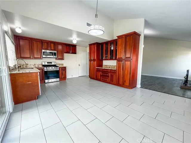 a kitchen with stainless steel appliances granite countertop a refrigerator a stove and a sink with cabinets