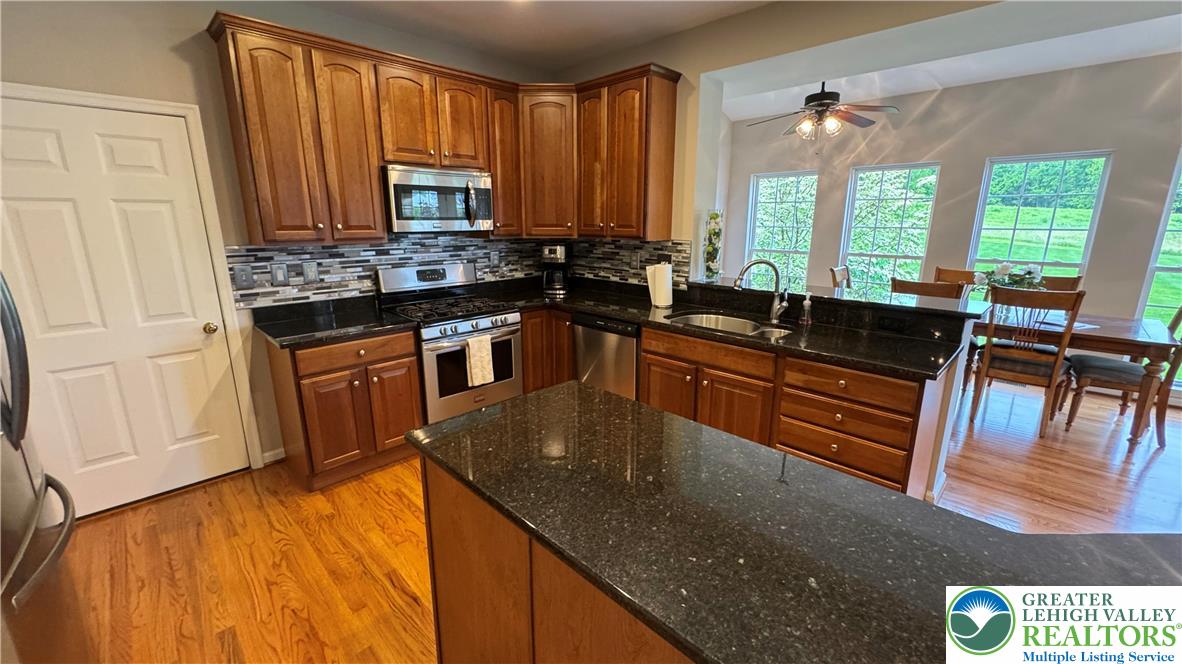 135 Clover Hollow Road Easton, PA 18045 - Photo 49 of 66 a kitchen with stainless steel appliances granite countertop a sink a stove and a wooden cabinets