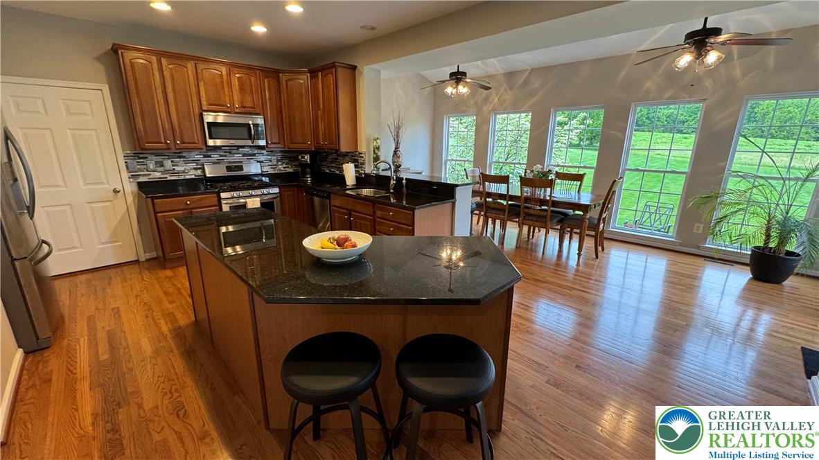 135 Clover Hollow Road Easton, PA 18045 - Photo 52 of 66 a kitchen with stainless steel appliances granite countertop a stove top oven a dining table and chairs with wooden floor