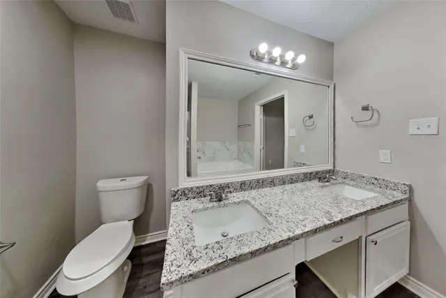a bathroom with a granite countertop sink a toilet and a mirror