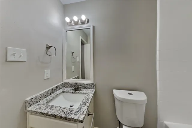 a bathroom with a granite countertop sink a toilet and mirror