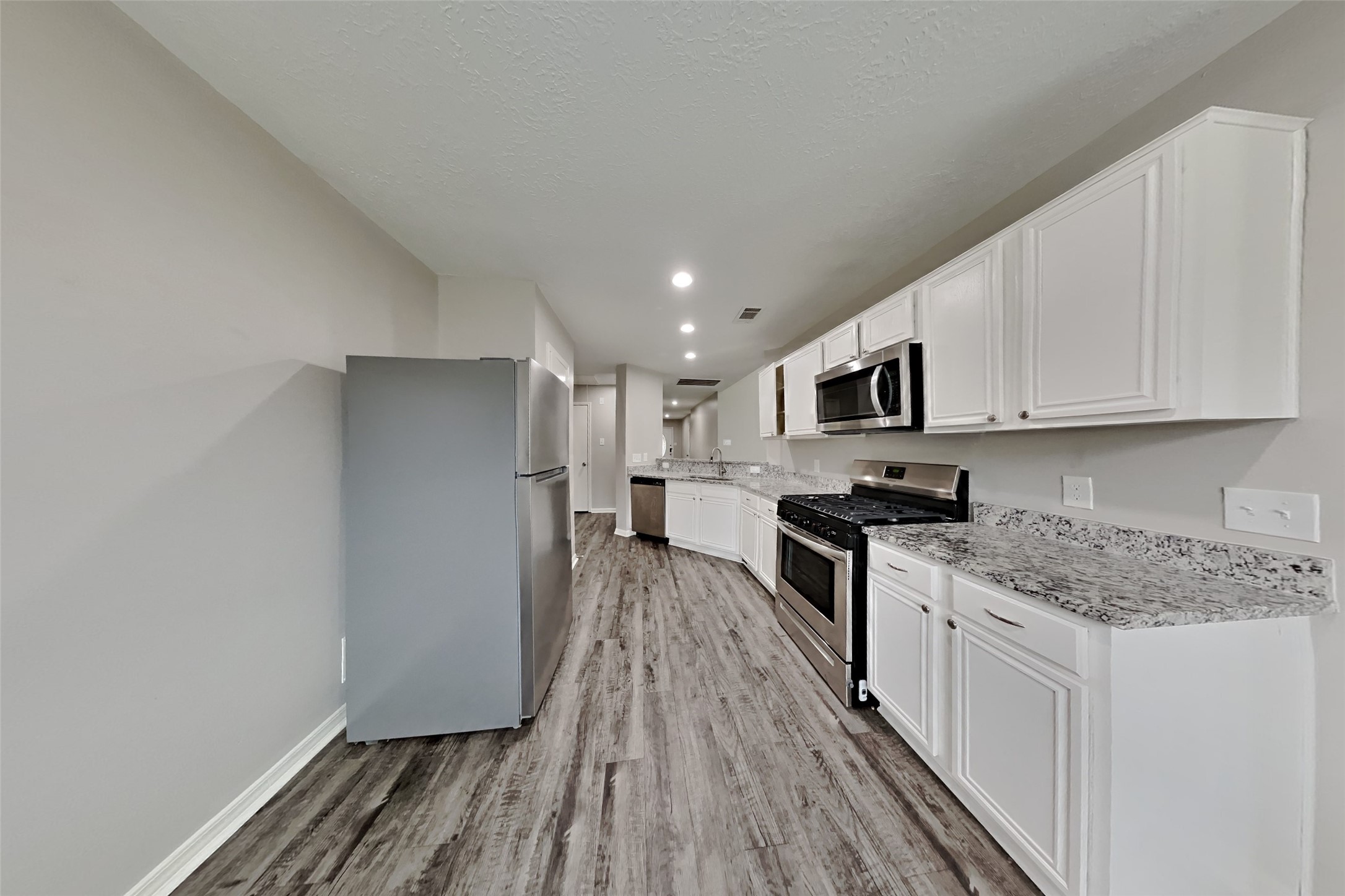 3413 Jan Court Katy, TX 77493 - Photo 4 of 18 a kitchen with stainless steel appliances granite countertop a stove top oven a sink dishwasher and a refrigerator with wooden floor