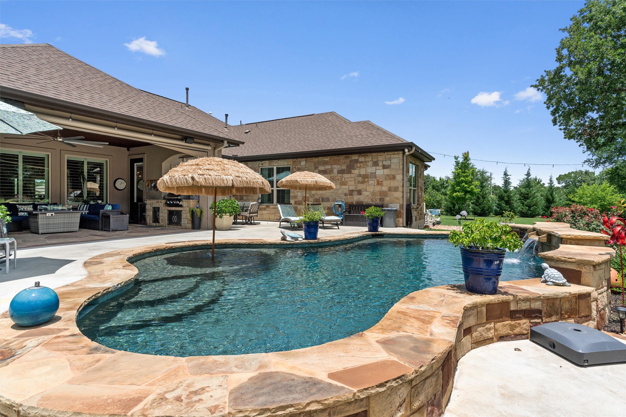 104 Adobe Cove Georgetown, TX 78633 - Photo 34 of 40 An inviting pool area with a stone patio, lush landscaping, and an outdoor kitchen.