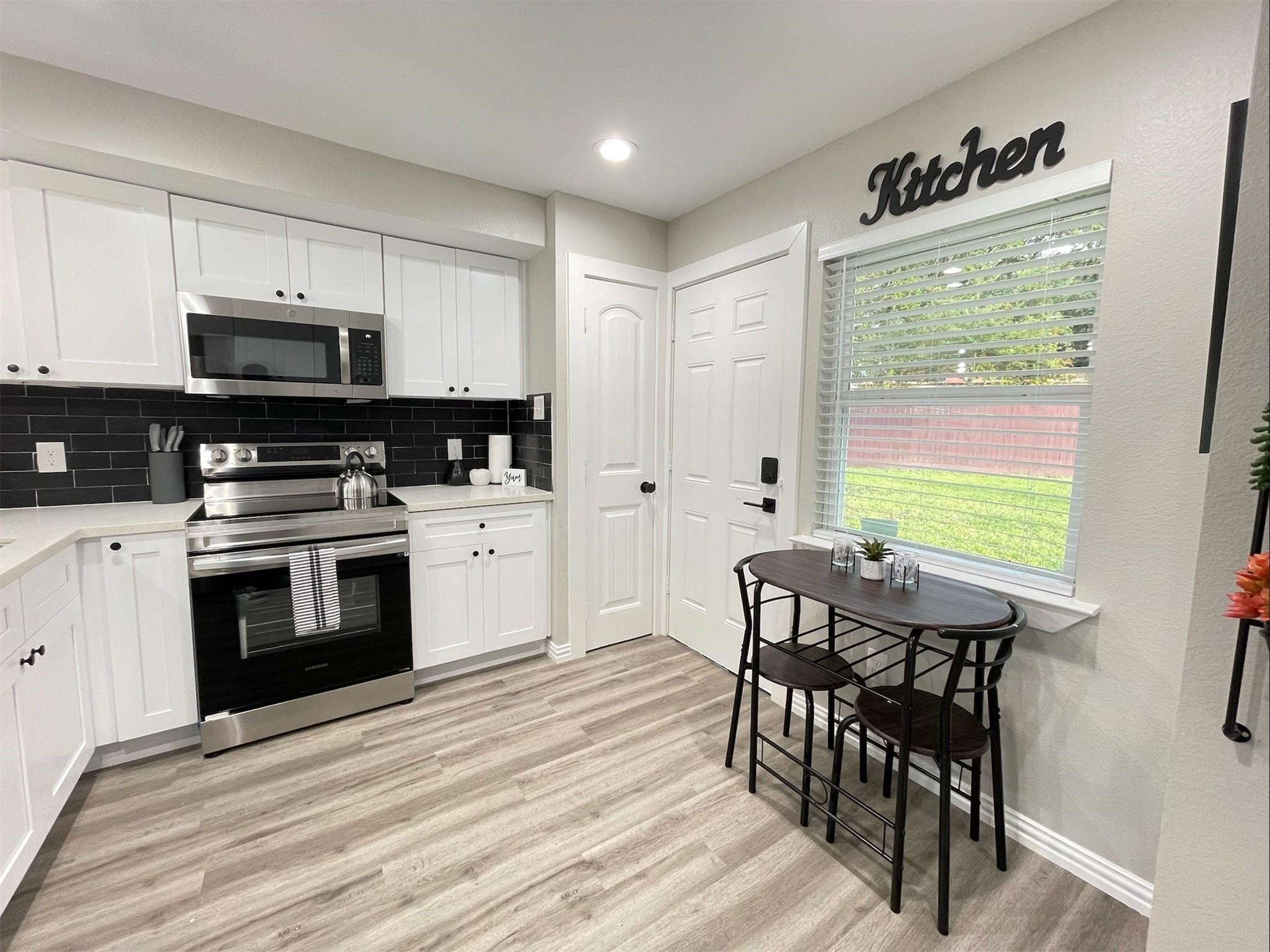4326 Alconbury Lane, Unit 8 Houston, TX 77021 - Photo 5 of 28 a kitchen with stainless steel appliances a stove a sink a microwave a dining table and chairs
