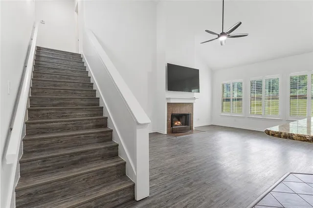 a view of an empty room with wooden floor fireplace and a window