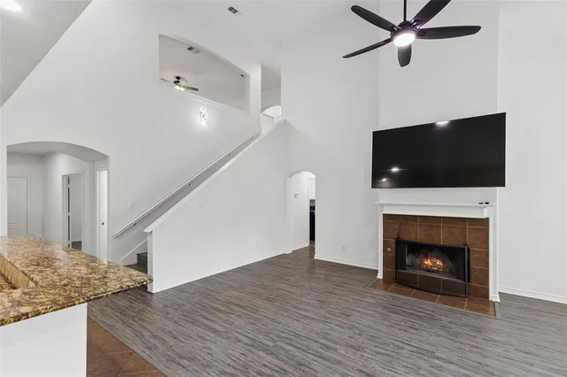 a view of a livingroom with a fireplace a ceiling fan and wooden floor