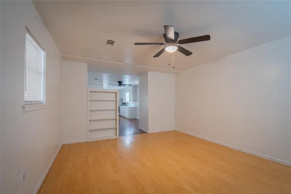 an empty room with a window and ceiling fan