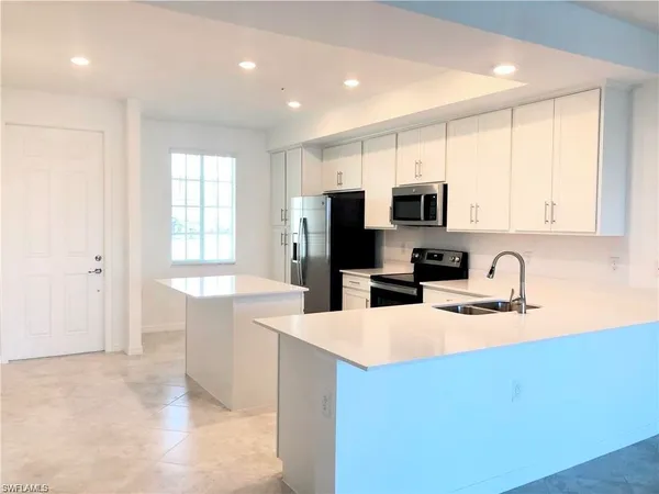 a kitchen with granite countertop a stove a sink a microwave a refrigerator a counter space and cabinets