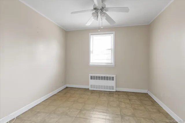 an empty room with a chandelier fan and windows