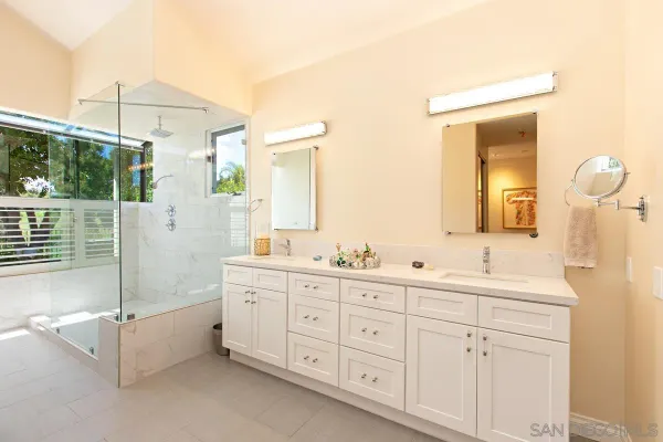 a spacious bathroom with double vanity a mirror a bathtub and a shower