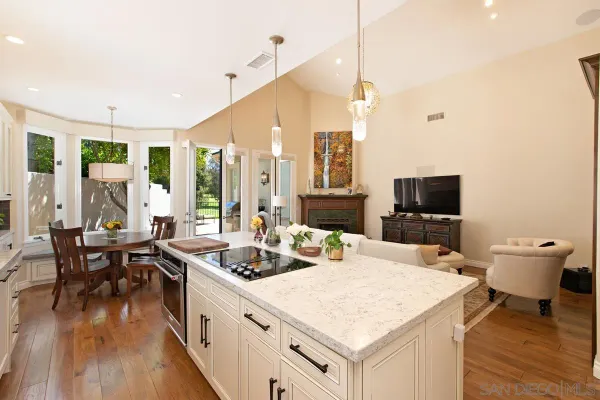 a kitchen with a stove a sink and white cabinets with wooden floor