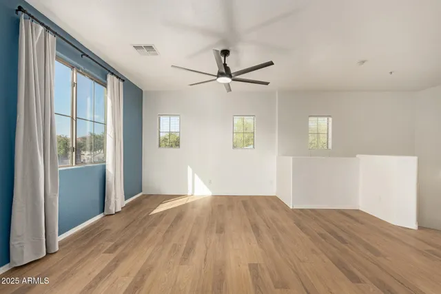 a view of a bedroom with wooden floor and a ceiling fan