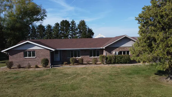 a front view of a house with yard and trees in the background