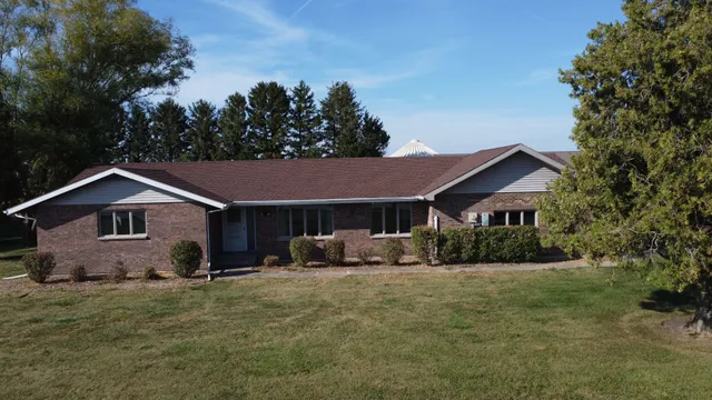 a front view of a house with yard and trees in the background