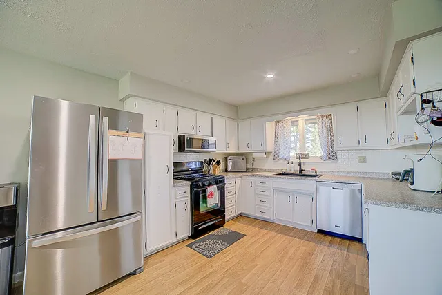 a kitchen with stainless steel appliances granite countertop a refrigerator a stove a sink dishwasher and a refrigerator with wooden floor