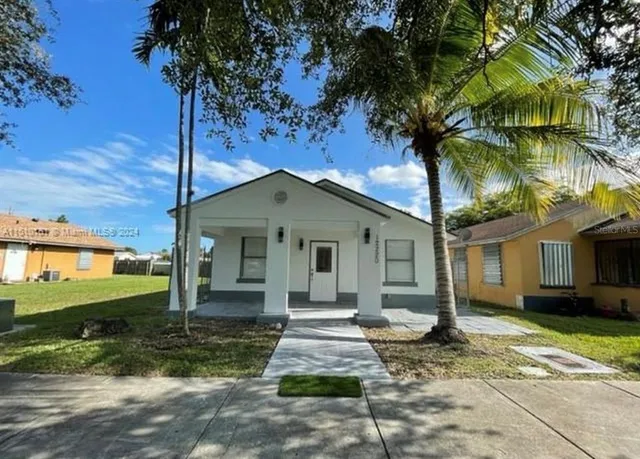 a front view of a house with a yard and potted plants