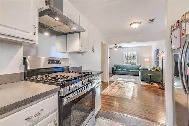 a kitchen with stainless steel appliances granite countertop a stove and a view of living room