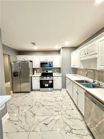a large kitchen with stainless steel appliances kitchen island granite countertop a sink and cabinets