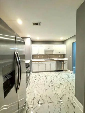 a kitchen with stainless steel appliances kitchen island granite countertop a refrigerator and cabinets