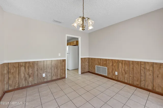 a view of an empty room with chandelier fan