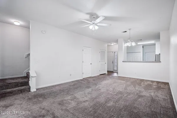 an empty room with chandelier fan and windows