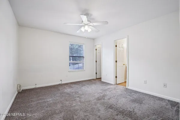 an empty room with windows and fan