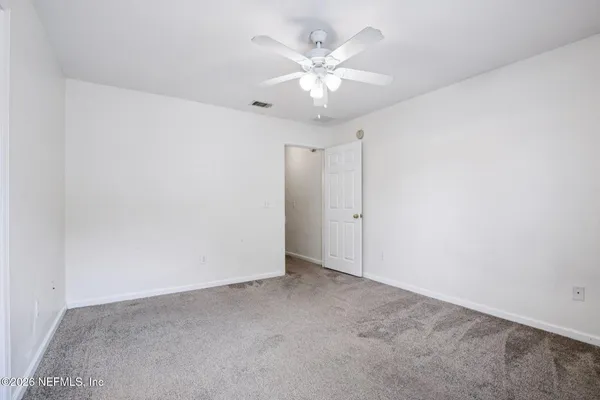 an empty room with a chandelier fan and windows