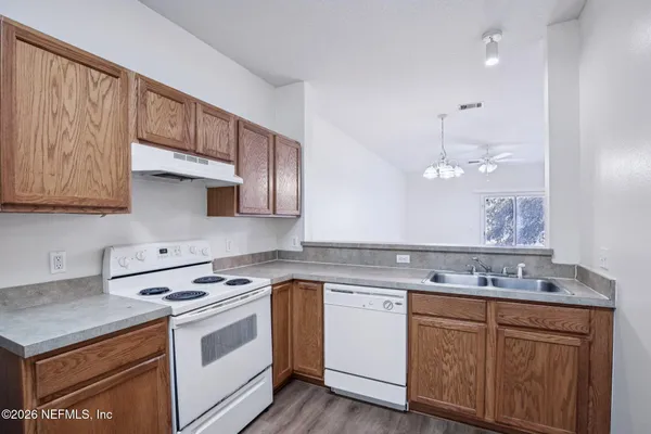 a kitchen with stainless steel appliances granite countertop a sink a stove a refrigerator and island with wooden cabinets