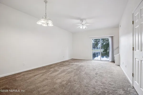 an empty room with chandelier fan and windows