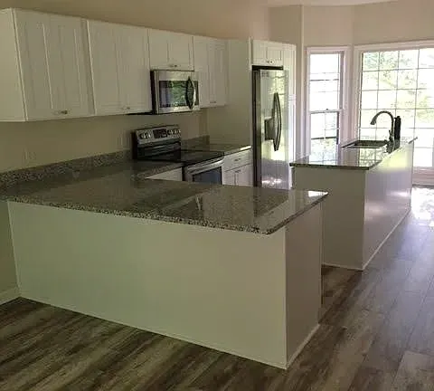 a kitchen with kitchen island granite countertop a sink cabinets and wooden floor