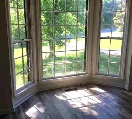 a view of an empty room with wooden floor and a window