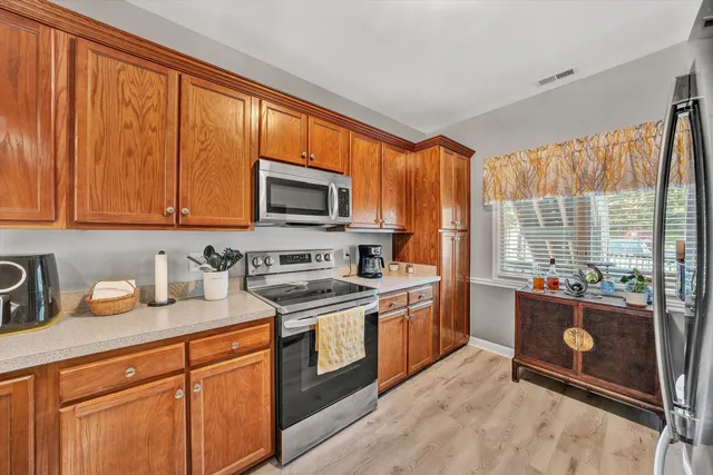 a kitchen with granite countertop wooden cabinets stainless steel appliances a sink and a large window