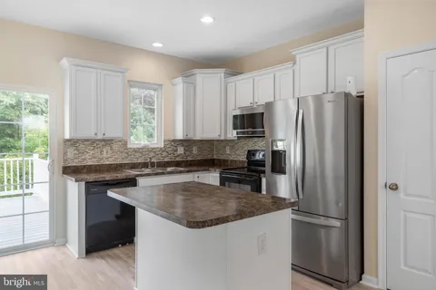 a kitchen with granite countertop a refrigerator stove and microwave