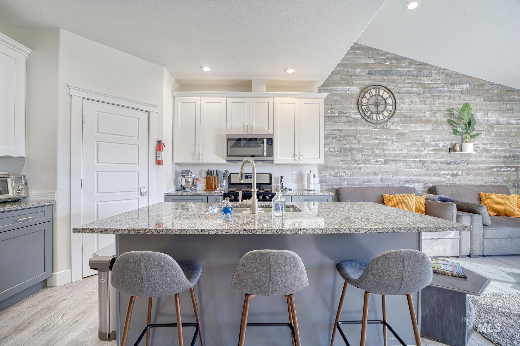 1087 Easy Avenue Twin Falls, ID 83301 - Photo 25 of 25 Kitchen featuring light stone countertops, a center island with sink, gray cabinetry, light wood-style flooring, and open floor plan
