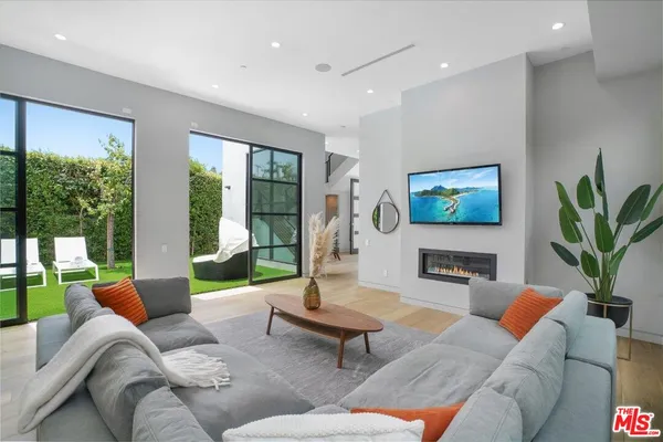 a living room with furniture floor to ceiling window and a flat screen tv