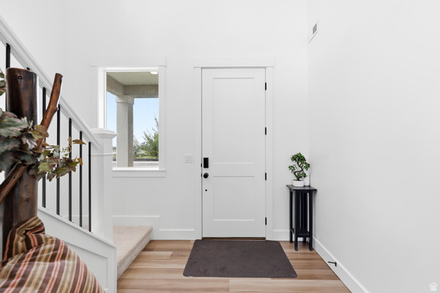 347 Ropelato Drive Logan, UT 84321 - Photo 4 of 46 Entryway featuring a solid panel door, wood-finish flooring, and white baseboards
